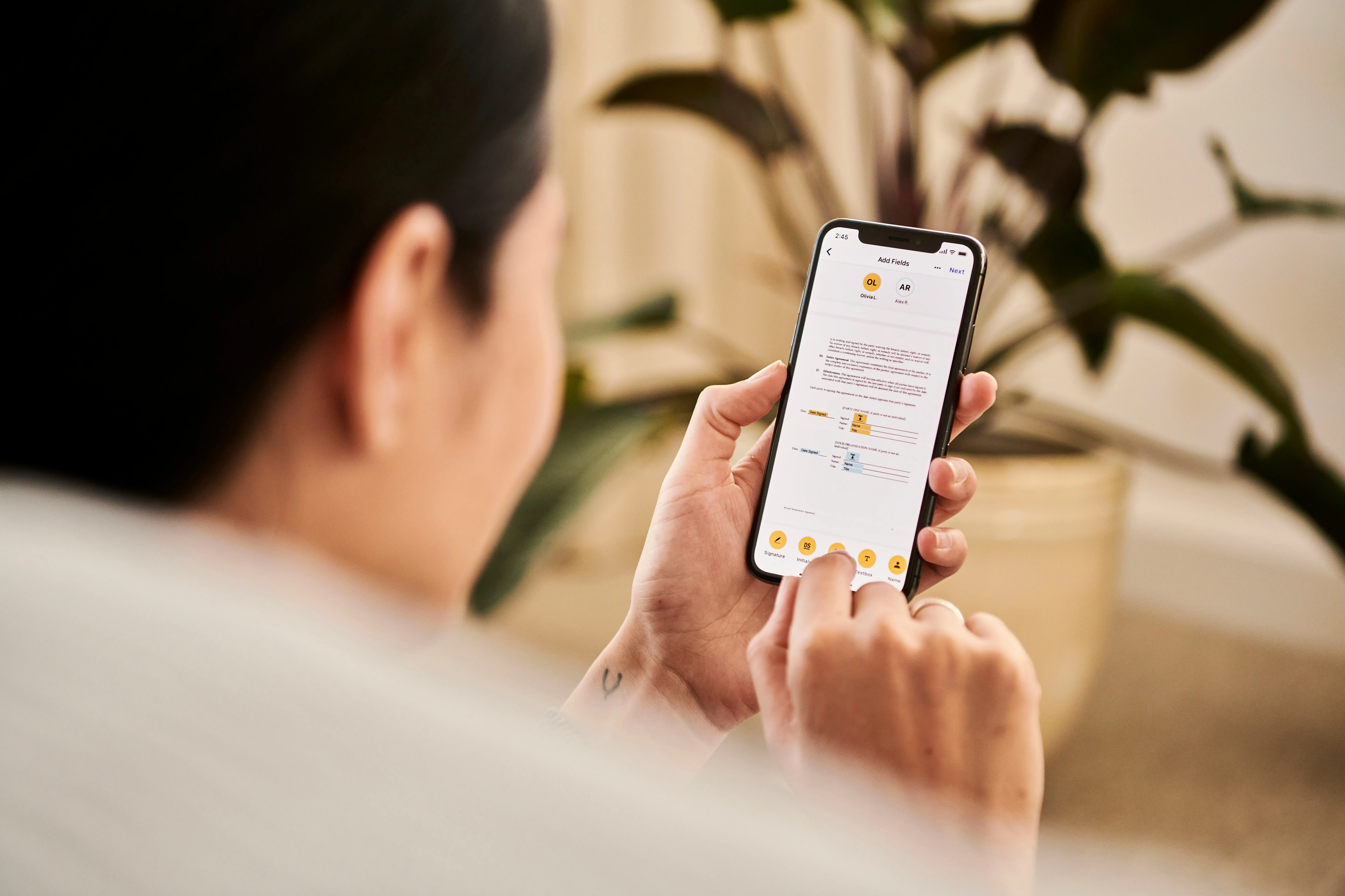 A person handling paperwork on their phone, sitting at home.